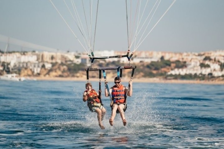 a man holding a kite while standing in a body of water